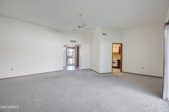 carpeted spare room with a towering ceiling and ceiling fan