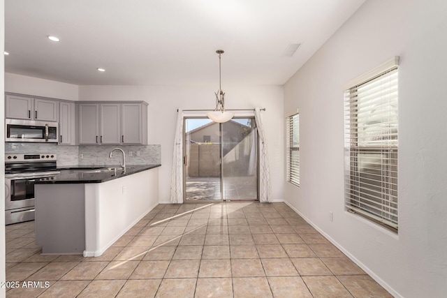 kitchen with backsplash, pendant lighting, light tile patterned flooring, sink, and stainless steel appliances