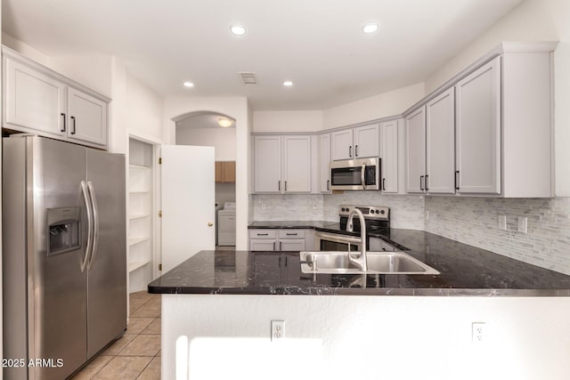 kitchen featuring sink, backsplash, appliances with stainless steel finishes, and kitchen peninsula