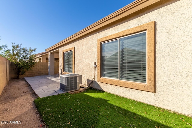 view of home's exterior with a patio area, central AC unit, and a lawn