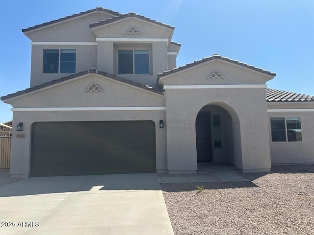 mediterranean / spanish-style home featuring concrete driveway, a tiled roof, and stucco siding
