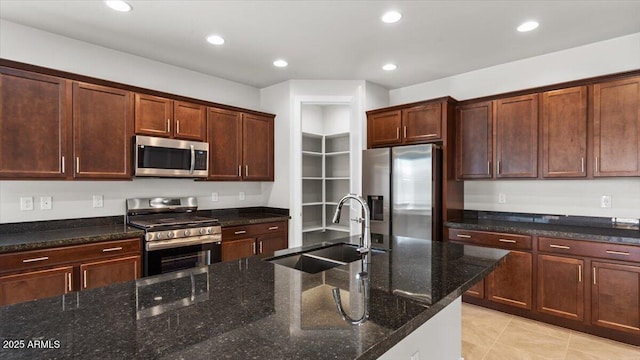kitchen with a sink, dark stone counters, recessed lighting, appliances with stainless steel finishes, and light tile patterned floors