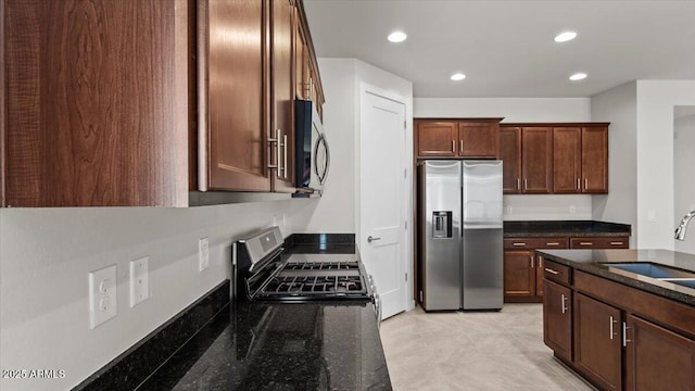 kitchen with recessed lighting, stainless steel appliances, a sink, and dark stone countertops