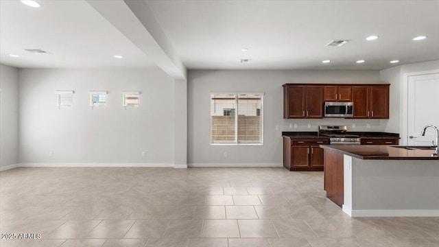 kitchen featuring dark countertops, visible vents, a sink, baseboards, and appliances with stainless steel finishes