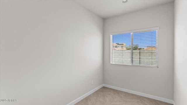 unfurnished room with baseboards and light carpet