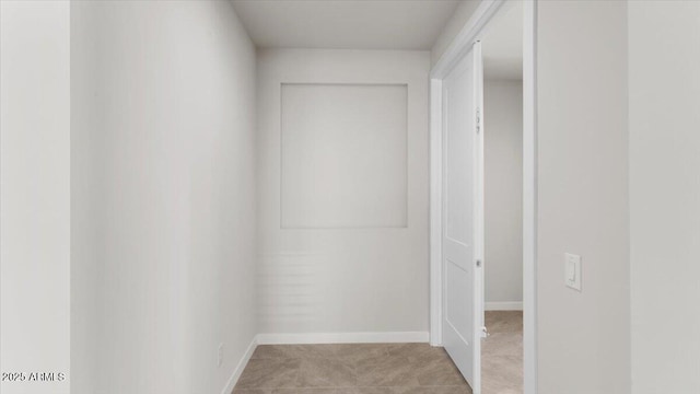 hallway featuring baseboards and light carpet