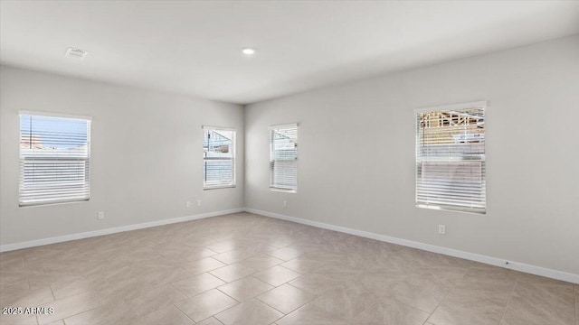 empty room featuring baseboards and light tile patterned floors