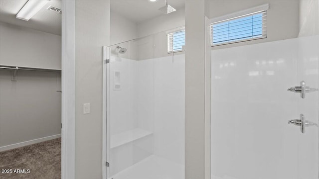 full bathroom with a walk in closet, baseboards, visible vents, and a stall shower