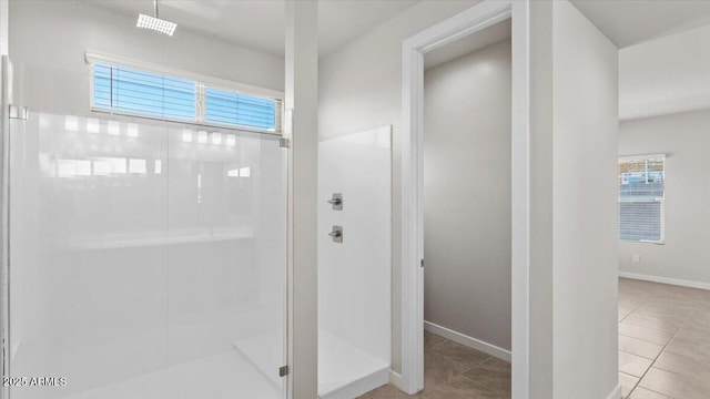 bathroom featuring baseboards, tile patterned flooring, and a stall shower