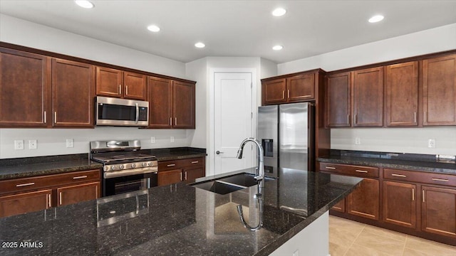 kitchen with recessed lighting, stainless steel appliances, light tile patterned floors, a sink, and dark stone counters