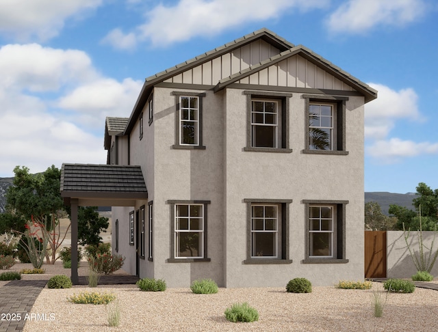 view of front of house with board and batten siding, fence, and stucco siding