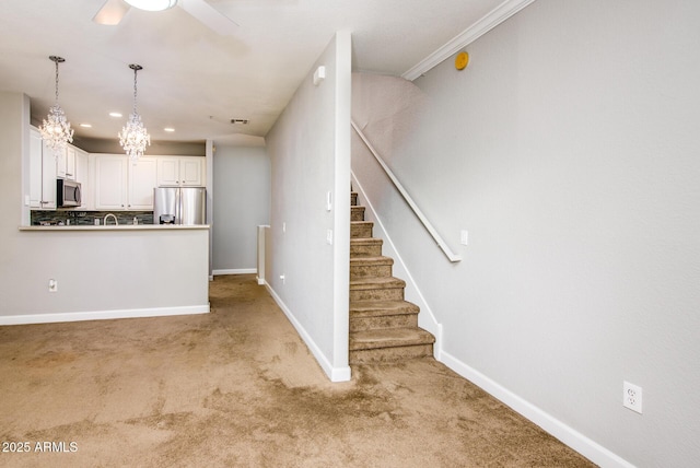 kitchen with decorative light fixtures, light carpet, appliances with stainless steel finishes, ceiling fan, and white cabinets