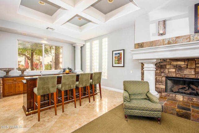 bar featuring coffered ceiling, a stone fireplace, and beamed ceiling