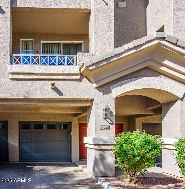 view of exterior entry featuring a garage and a balcony