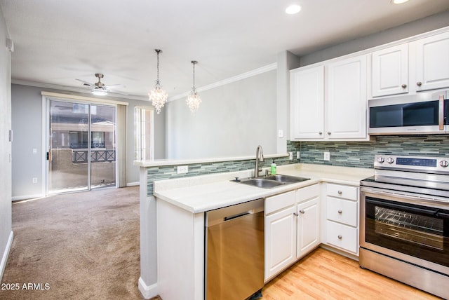 kitchen featuring sink, decorative light fixtures, appliances with stainless steel finishes, kitchen peninsula, and white cabinets