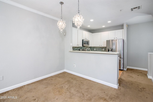 kitchen featuring light carpet, kitchen peninsula, pendant lighting, stainless steel appliances, and white cabinets