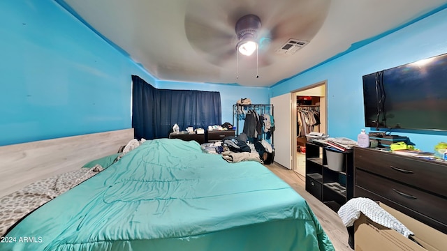 bedroom featuring a walk in closet, light hardwood / wood-style flooring, a closet, and ceiling fan