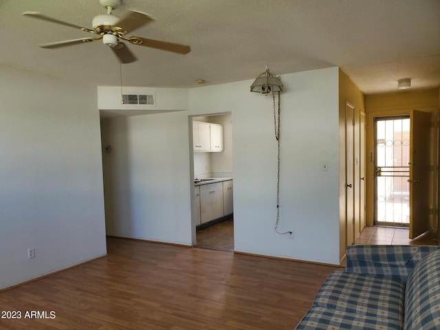 unfurnished living room featuring wood-type flooring, a textured ceiling, and ceiling fan