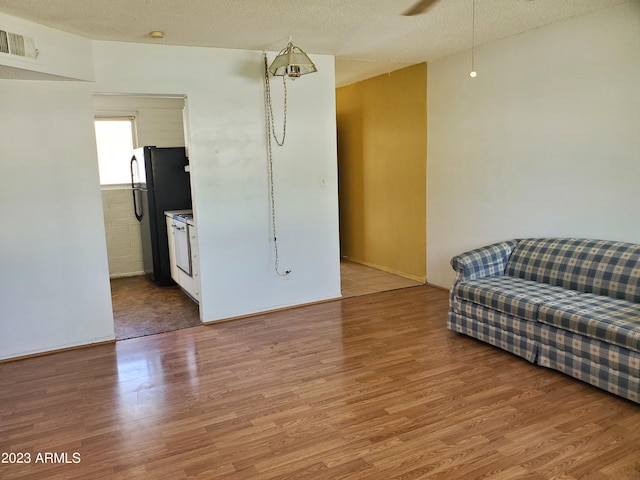 living room featuring ceiling fan, hardwood / wood-style flooring, and a textured ceiling