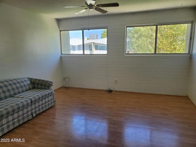 living room featuring hardwood / wood-style flooring, ceiling fan, and a textured ceiling