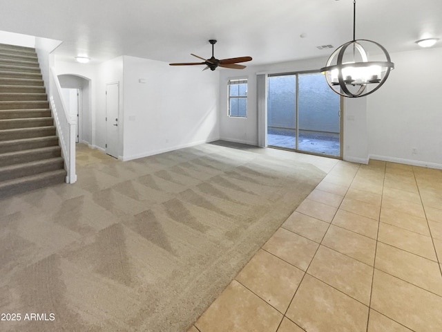 unfurnished living room with ceiling fan with notable chandelier and light tile patterned floors