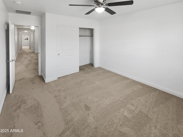 unfurnished bedroom featuring ceiling fan, a closet, and light carpet