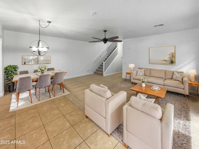 living room with ceiling fan with notable chandelier and light tile patterned floors