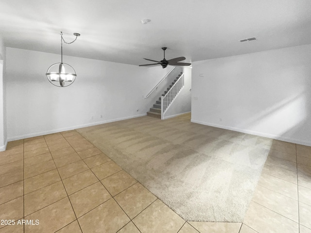 unfurnished living room with ceiling fan with notable chandelier and light tile patterned flooring