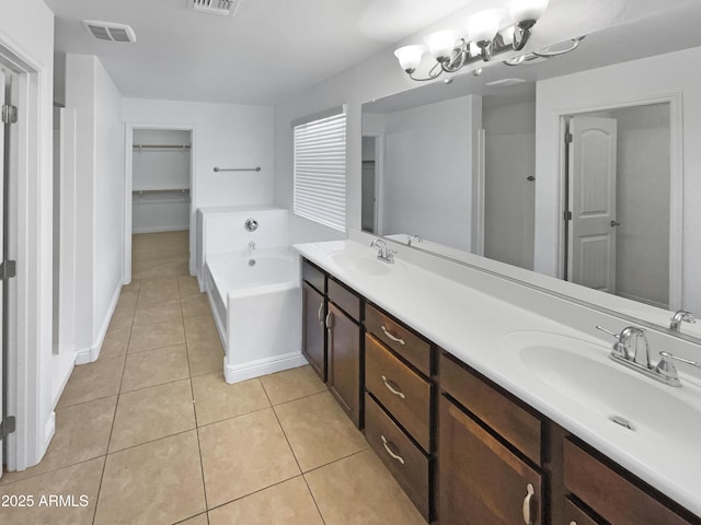 bathroom with a washtub, tile patterned floors, and vanity