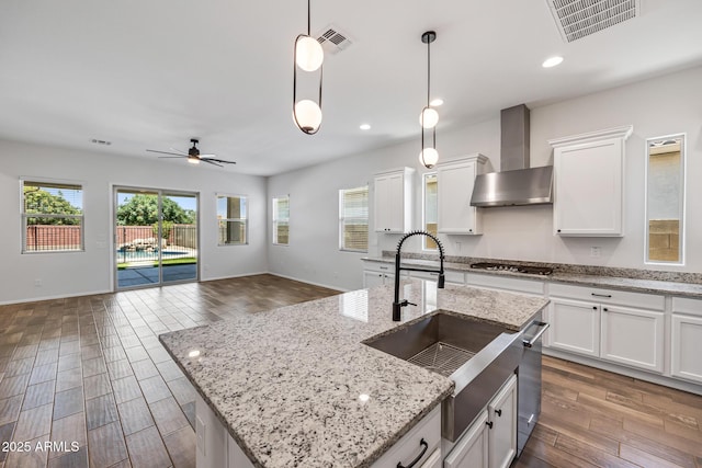 898 E Ladbroke Way, Gilbert, AZ 85297 - kitchen featuring wall chimney range hood, gas stovetop, a ceiling fan, open floor plan, and dark wood-style flooring