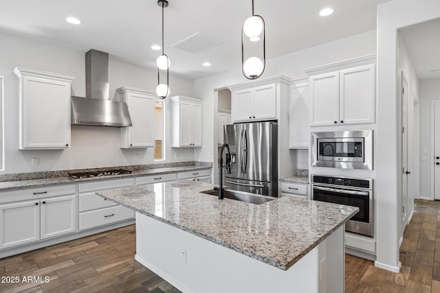 898 E Ladbroke Way, Gilbert, AZ 85297 - kitchen featuring appliances with stainless steel finishes, wall chimney exhaust hood, dark wood finished floors, white cabinets, and a kitchen island with sink