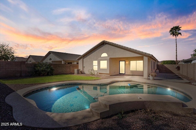 pool at dusk with a patio area, a yard, a fenced backyard, and a fenced in pool