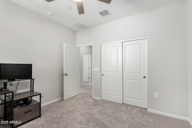 bedroom featuring light colored carpet, ceiling fan, and a closet