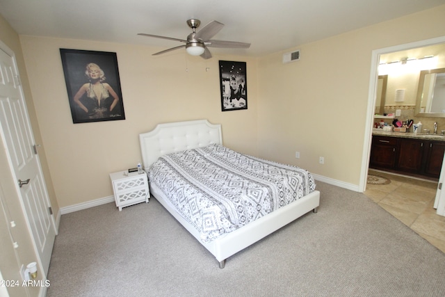 bedroom featuring light colored carpet, ceiling fan, sink, and ensuite bath