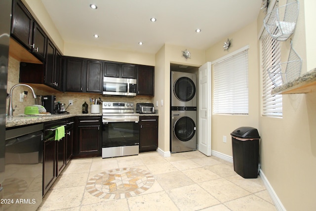 9450 N 95th St Unit 219, Scottsdale, AZ 85258 - kitchen with appliances with stainless steel finishes, stacked washer / drying machine, decorative backsplash, baseboards, and recessed lighting