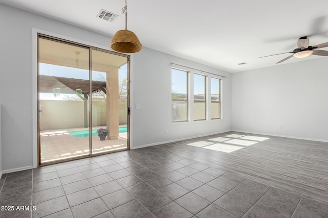 unfurnished room featuring ceiling fan, visible vents, baseboards, and dark tile patterned floors