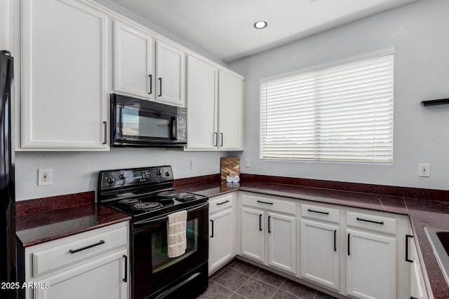 kitchen with dark countertops, white cabinetry, black appliances, and dark tile patterned flooring