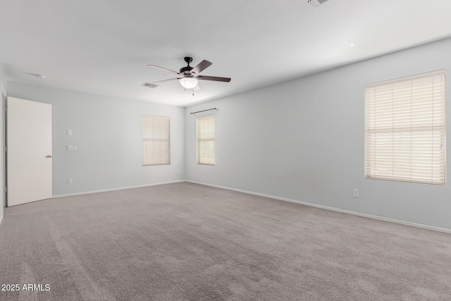 carpeted spare room with visible vents, baseboards, and ceiling fan