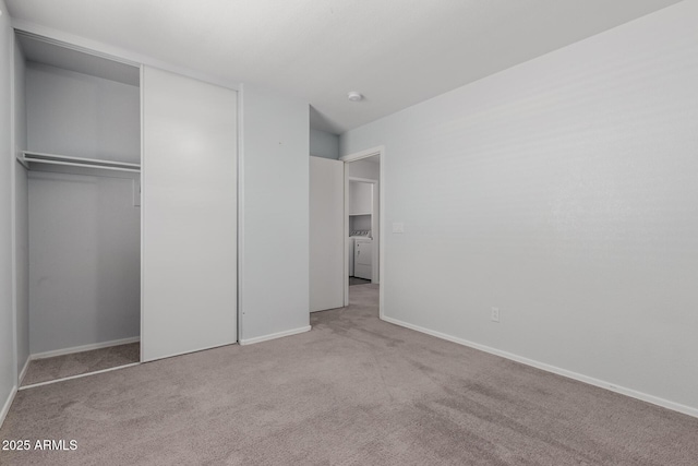 unfurnished bedroom with baseboards, a closet, carpet floors, and washer / dryer