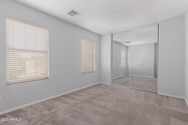 unfurnished bedroom featuring visible vents, baseboards, a closet, and carpet flooring