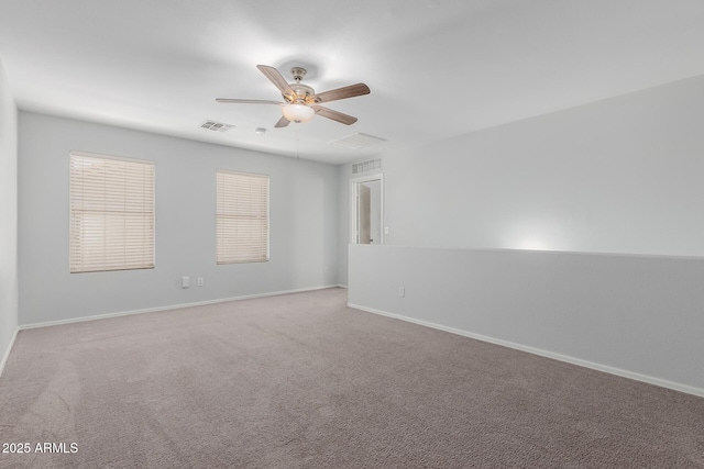 carpeted spare room with visible vents, baseboards, and ceiling fan