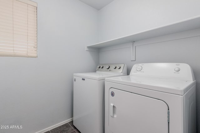 laundry room featuring baseboards, separate washer and dryer, dark tile patterned floors, and laundry area