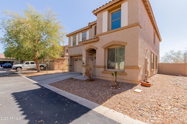 view of front facade with stucco siding, driveway, fence, a garage, and a tiled roof