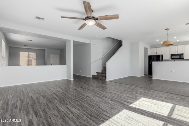 unfurnished living room with visible vents, baseboards, dark wood finished floors, and stairs