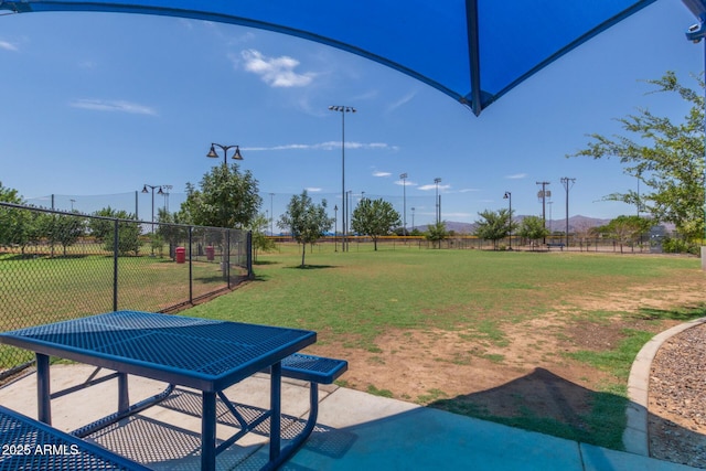 view of property's community featuring a patio, a lawn, and fence