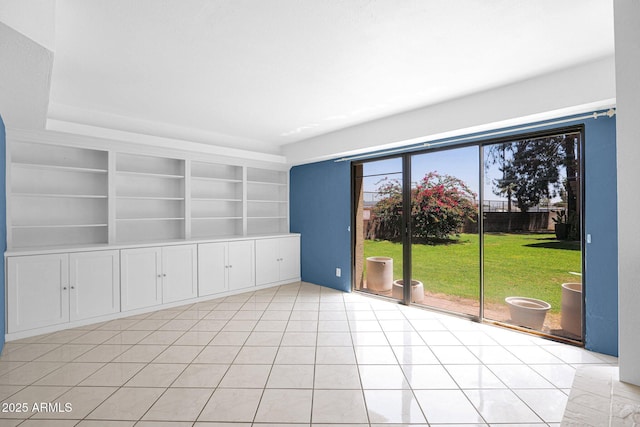 empty room featuring built in shelves and light tile patterned floors
