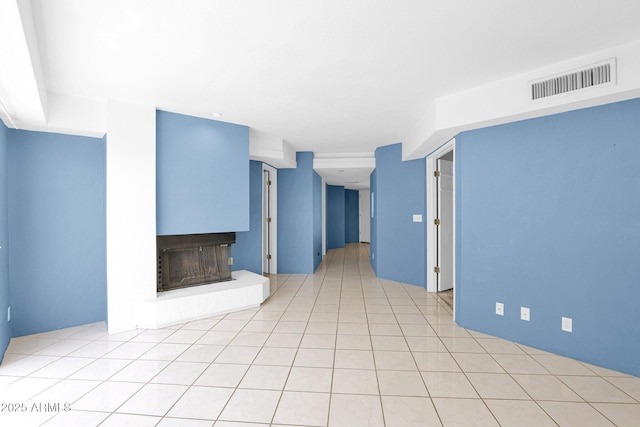 unfurnished living room featuring a fireplace with raised hearth and light tile patterned floors