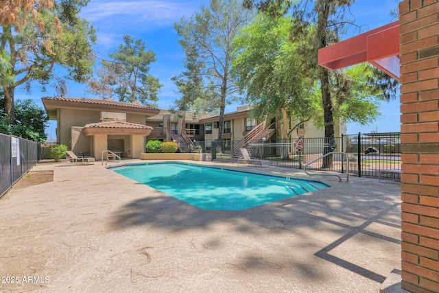 community pool featuring stairway, fence, and a patio