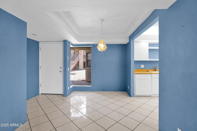 unfurnished room featuring light tile patterned flooring, a raised ceiling, and a sink