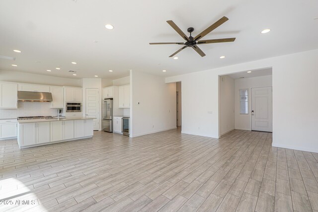 unfurnished living room with light hardwood / wood-style floors, ceiling fan, and sink